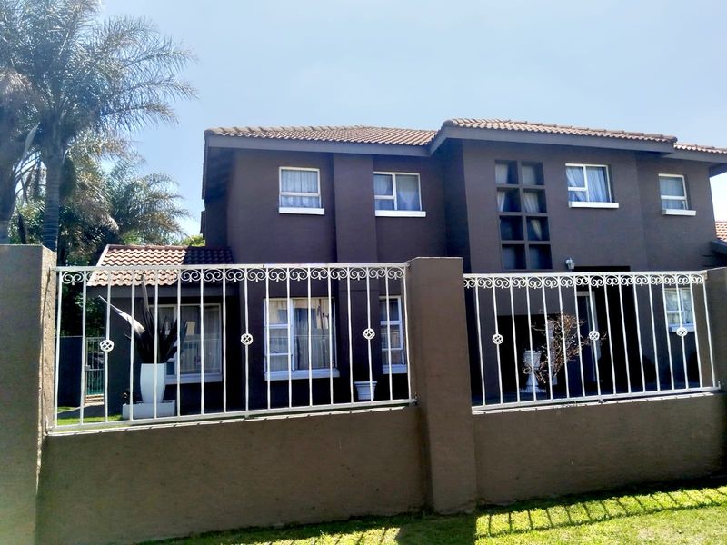Front elevation of a two-story residential apartment building featuring dark painted exterior walls, a tiled roof, and secure metal perimeter fencing.