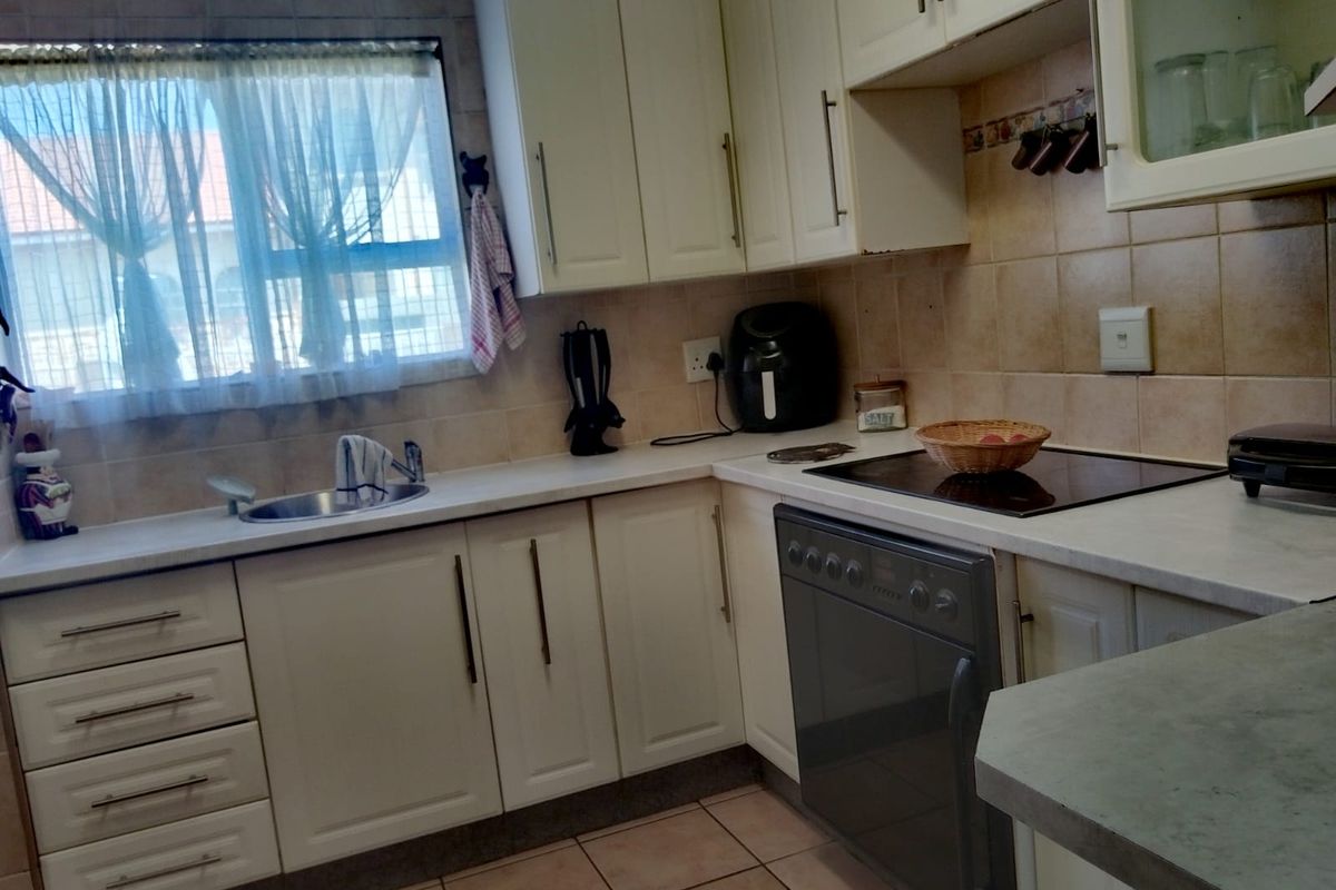 A functional kitchen featuring built-in cabinetry, laminate countertops, a ceramic hob, and an integrated oven with tiled backsplash and flooring.