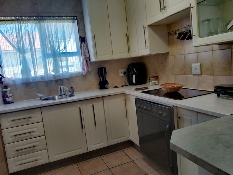 A functional kitchen featuring built-in cabinetry, laminate countertops, a ceramic hob, and an integrated oven with tiled backsplash and flooring.