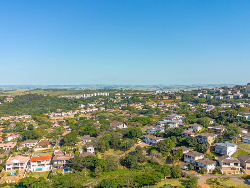 An elevated aerial view of a residential estate featuring established homes, lush greenery, and surrounding landscape.