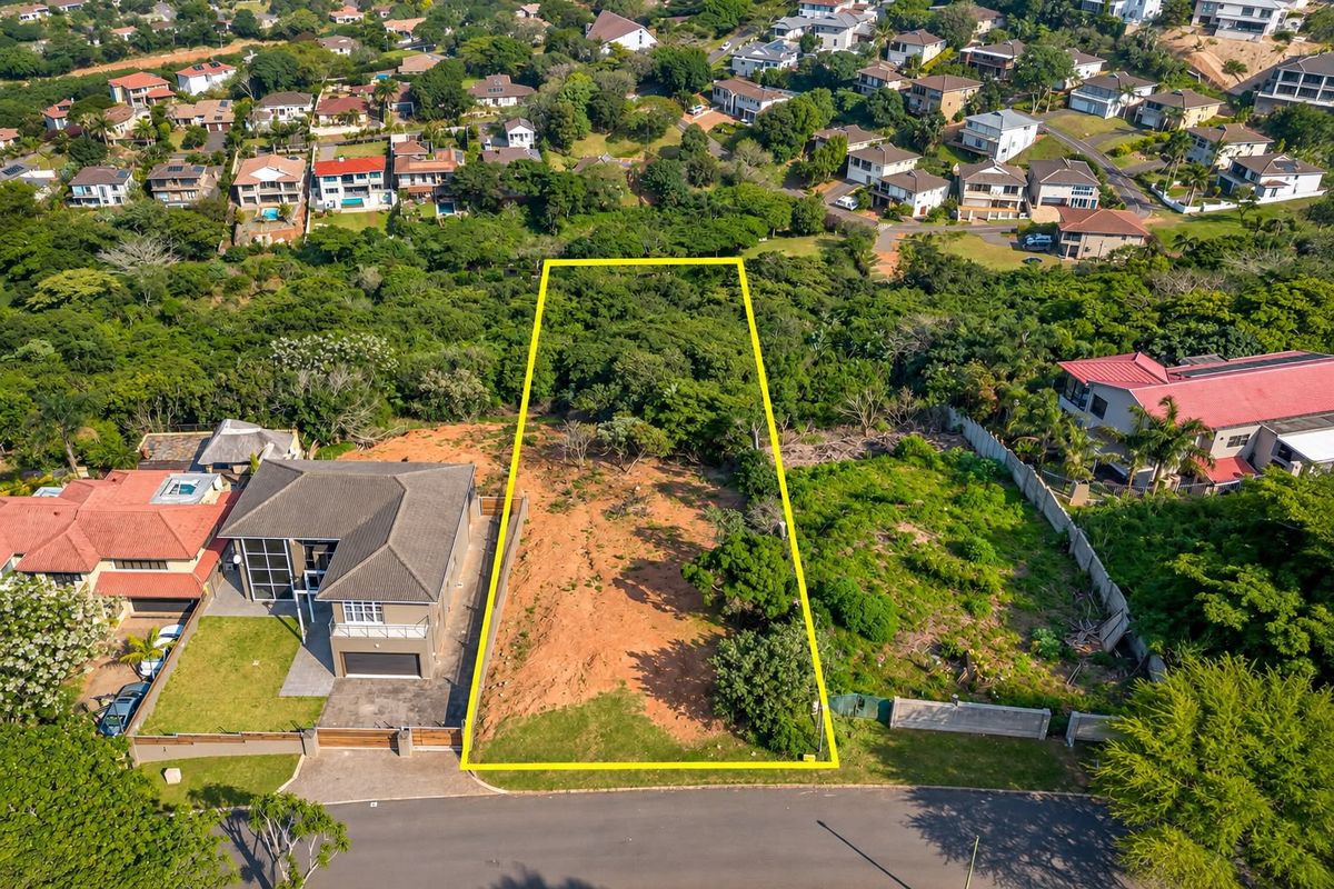 Aerial view of a vacant residential plot in a developed neighborhood, showing the property boundaries and surrounding vegetation.