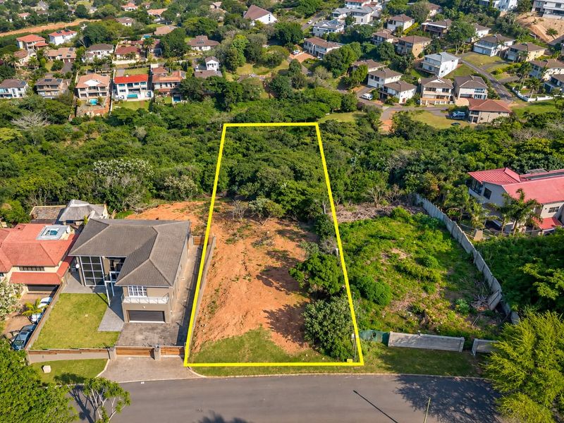 Aerial view of a vacant residential plot in a developed neighborhood, showing the property boundaries and surrounding vegetation.
