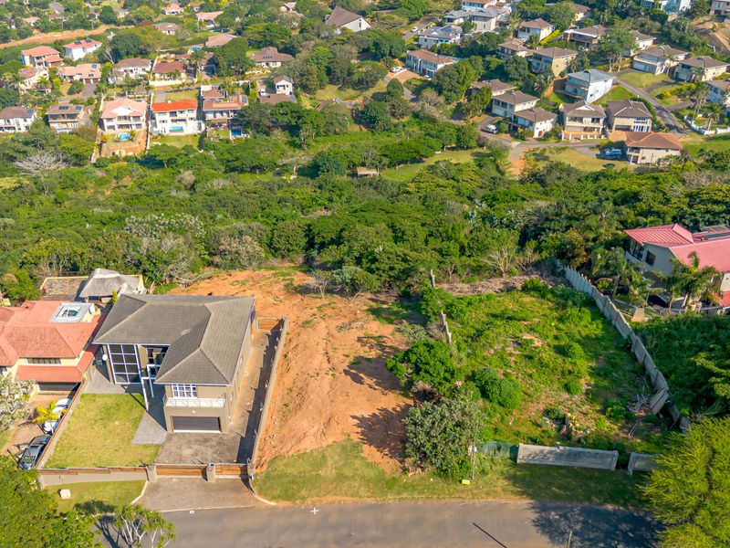 Aerial view of a vacant residential plot situated in a developed suburban neighborhood, featuring clear boundaries and access from the street.