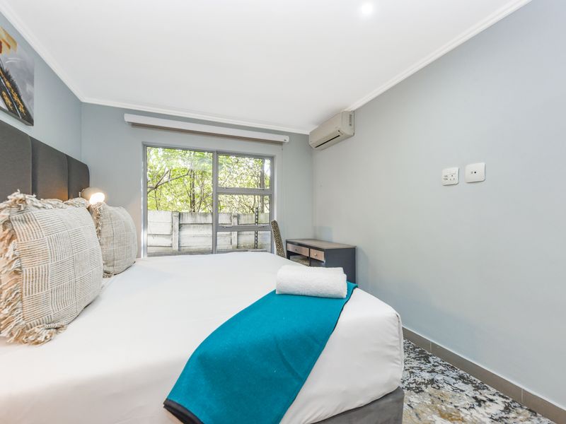 A well-maintained bedroom featuring tiled flooring, an air conditioning unit, and a large sliding window providing natural light.