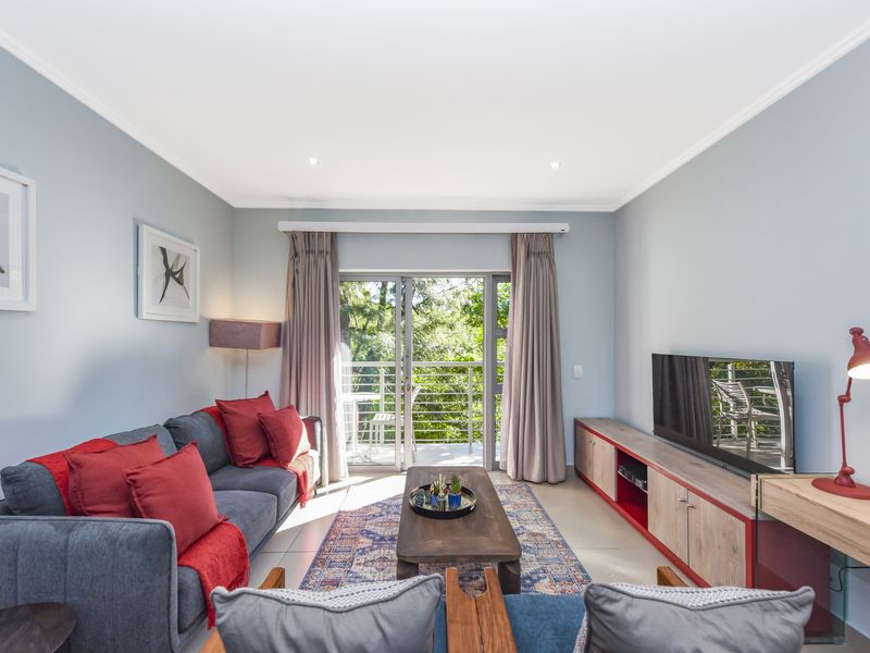 A bright and well-maintained living room featuring tiled flooring, recessed lighting, and a sliding glass door providing access to a private balcony.