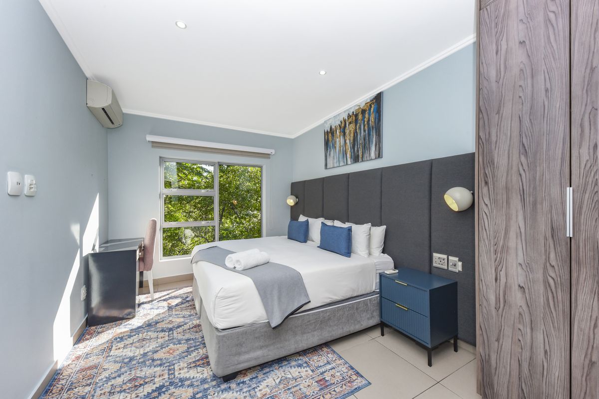 A well-maintained bedroom featuring a built-in wardrobe, air conditioning, recessed lighting, and a large window with natural light.