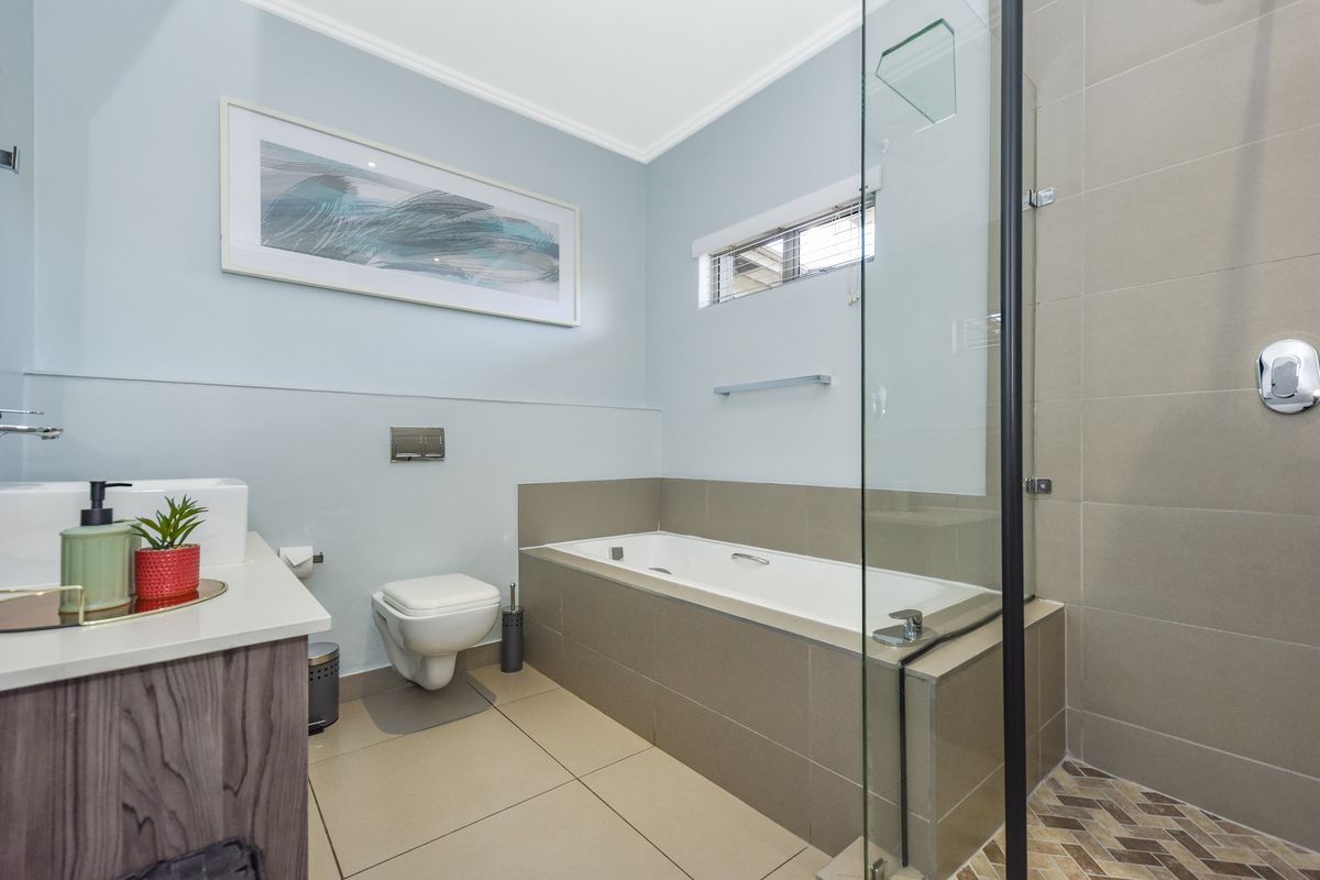 Modern bathroom featuring a built-in bathtub, separate glass-enclosed shower, wall-mounted toilet, and a vanity cabinet with contemporary tiled finishes.