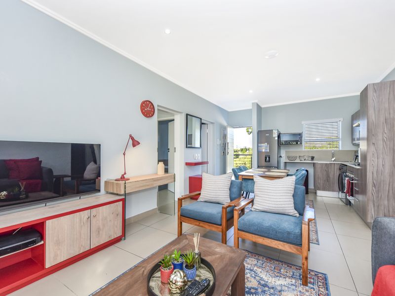 Spacious open-plan living area featuring tiled floors, recessed lighting, and a modern kitchen with integrated cabinetry and appliances.