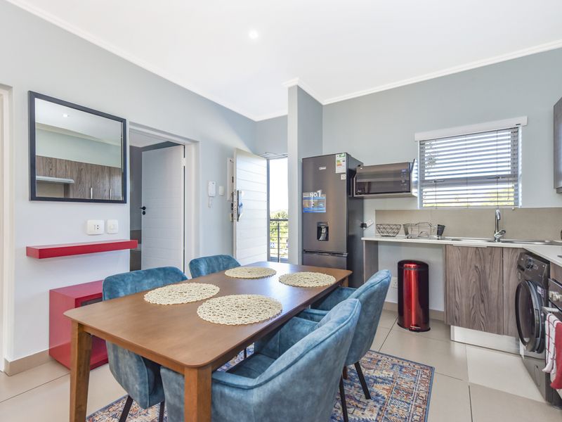 Modern open-plan living and dining area featuring a well-appointed kitchen with built-in cabinetry, integrated appliances, and sleek tiled flooring throughout.