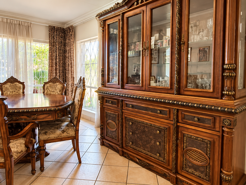 A formal dining room featuring ceramic tile flooring, crown molding, and large windows with security bars, offering a bright and traditional living space.