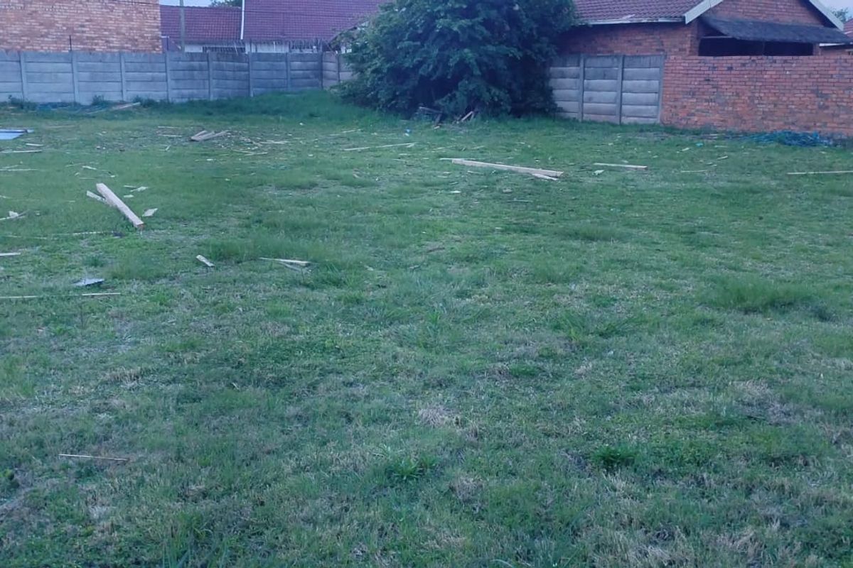 A vacant residential plot featuring grass coverage and established perimeter boundary walls, providing a clear space for future development.
