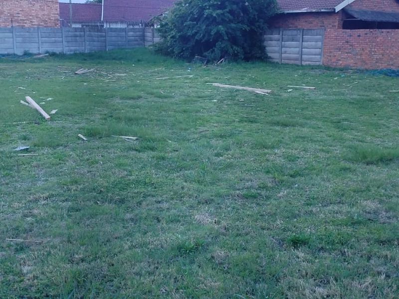 A vacant residential plot featuring grass coverage and established perimeter boundary walls, providing a clear space for future development.
