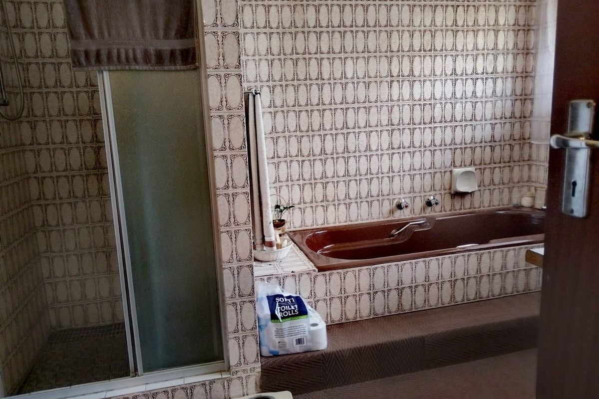 A dated bathroom featuring a built-in bathtub and a separate shower enclosure with patterned wall tiles throughout.