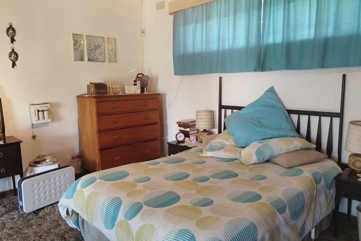 A bedroom featuring carpet flooring and a built-in wall heater, requiring cosmetic updates to modernize the space.