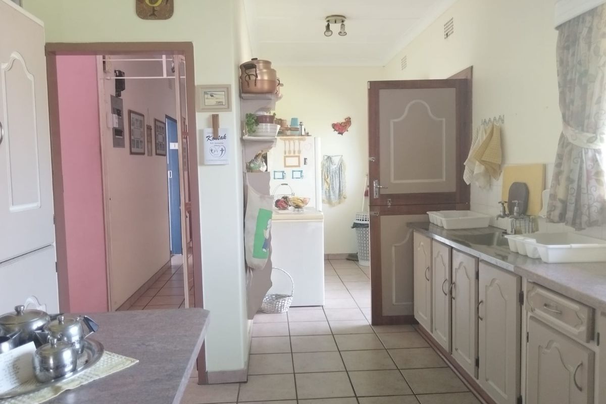 A functional kitchen featuring tiled flooring, built-in cabinetry with laminate countertops, and a classic stable door leading to the adjacent living area.