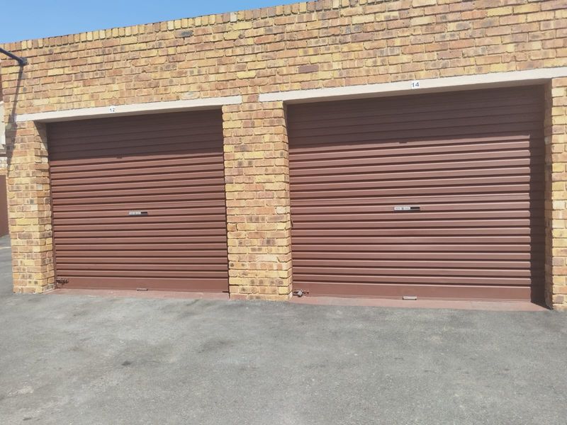 A view of two secure roller shutter garage doors set within a brick exterior structure.
