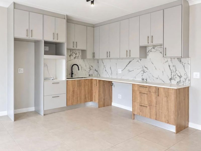 Modern kitchen featuring two-tone cabinetry, marble-look splashback, stone countertops, and high-quality finishes in an open-plan layout.