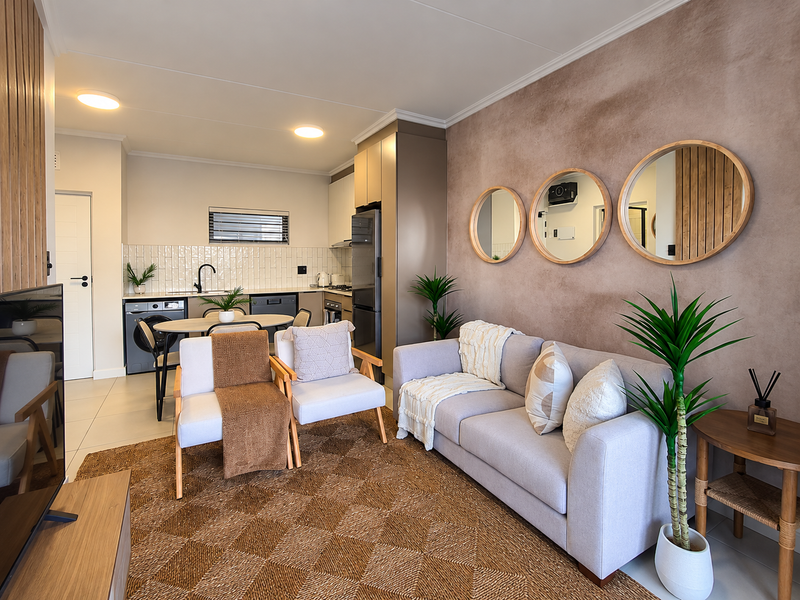 Modern open-plan living area featuring a well-appointed kitchen with subway tile backsplash, integrated appliances, and sleek cabinetry, seamlessly flowing into the comfortable lounge space.