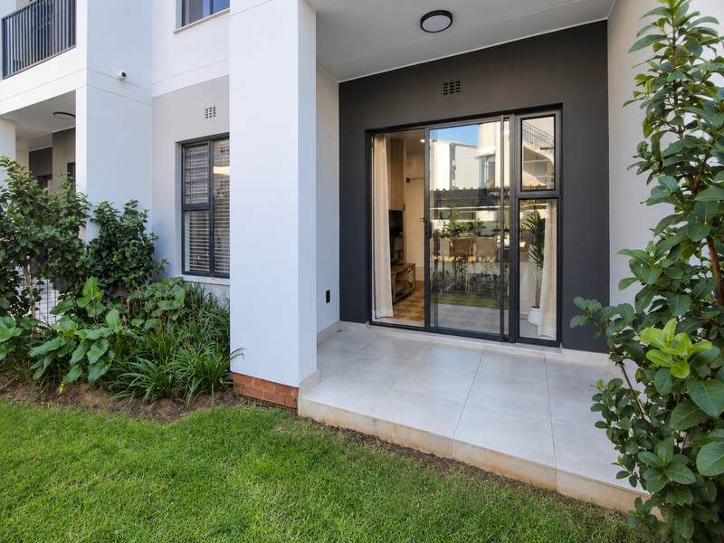 A modern ground floor patio featuring tiled flooring, sliding glass doors, and clean architectural finishes, providing seamless access to the garden area.