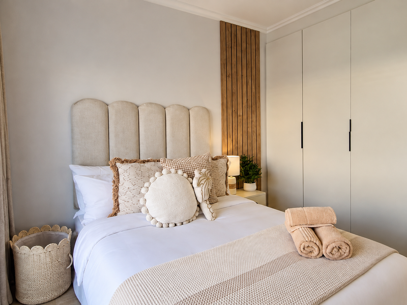 A well-appointed bedroom featuring a modern timber slat accent wall, integrated floor-to-ceiling wardrobe, and a neutral color palette.