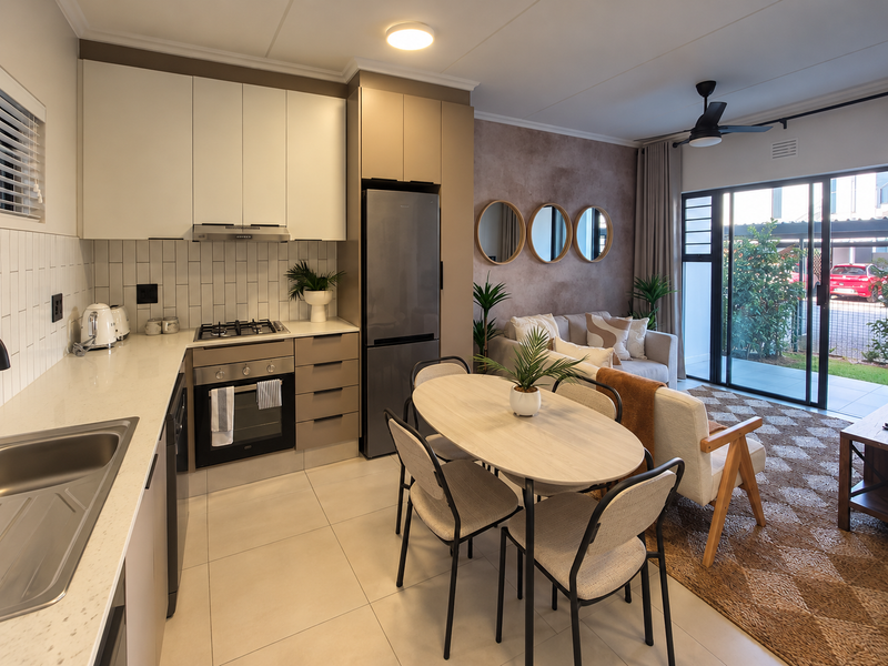 Modern open-plan kitchen and living area featuring sleek cabinetry, stone countertops, integrated appliances, and direct access to an outdoor patio through sliding glass doors.