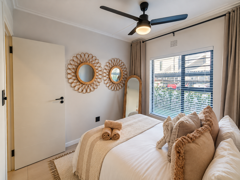 A well-maintained bedroom featuring a ceiling fan, neutral wall finishes, and a window with blinds, providing a bright and comfortable living space.