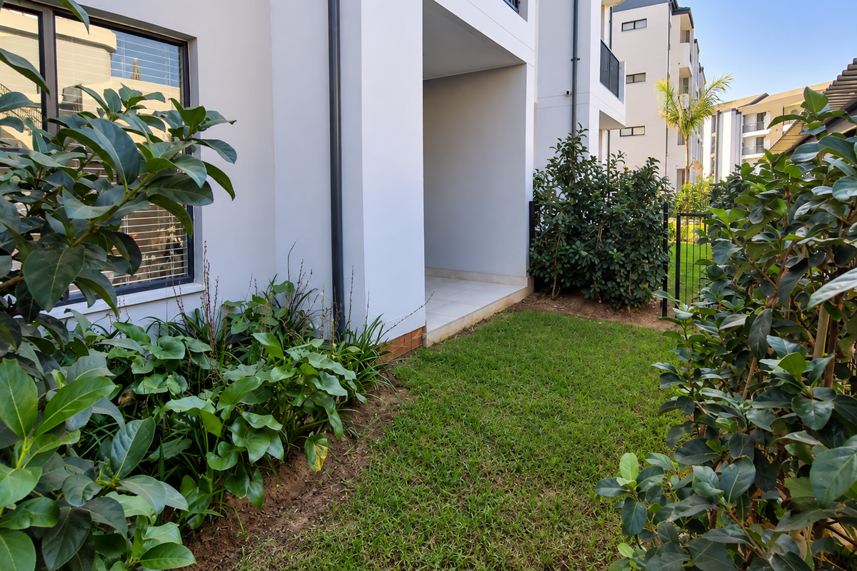A well-maintained ground floor apartment exterior featuring a private garden area and a tiled patio space.