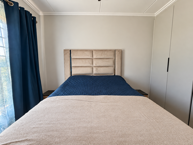 A well-maintained bedroom featuring a built-in wardrobe and decorative ceiling cornice, offering a clean and functional living space.