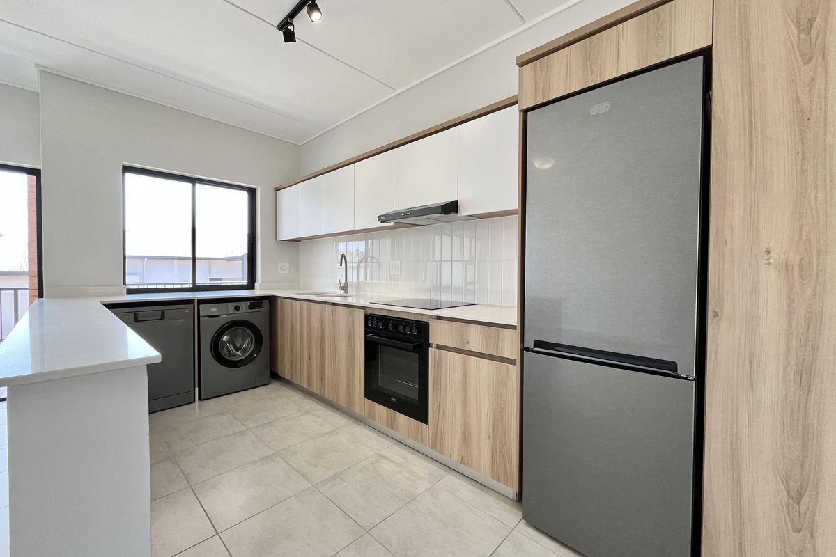 Modern kitchen featuring light wood-grain cabinetry, white quartz countertops, tiled backsplash, and integrated appliances including an oven, hob, and extractor fan.
