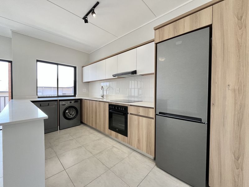Modern kitchen featuring light wood-grain cabinetry, white quartz countertops, tiled backsplash, and integrated appliances including an oven, hob, and extractor fan.