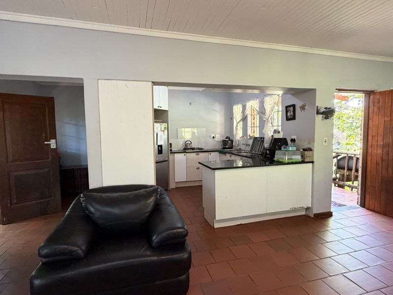 Open plan living and kitchen area featuring tiled flooring, timber ceiling, and a functional kitchen layout with stone countertops.