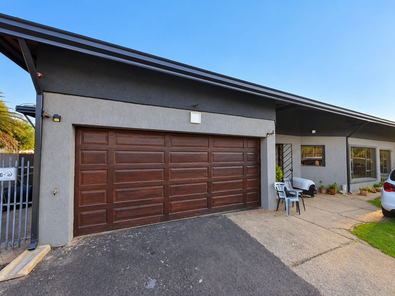 Front exterior view of the property featuring a dark wood-finish sectional garage door, concrete driveway, and modern grey textured facade.