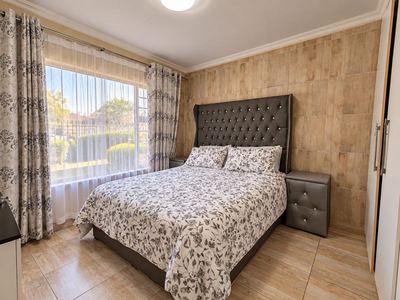 A well-maintained bedroom featuring tiled flooring, a tiled feature wall, and a built-in wardrobe, offering a clean and functional living space.