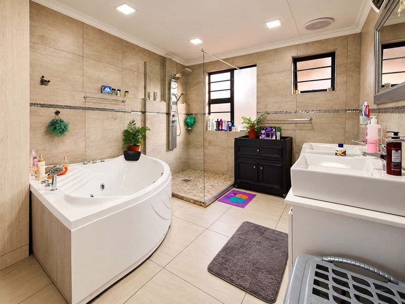 Modern bathroom featuring a corner spa bath, a spacious walk-in shower with pebble flooring, and a double vanity with ample storage.