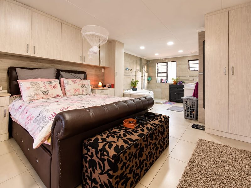 Spacious bedroom featuring extensive built-in cabinetry and an integrated open-plan en-suite bathroom with a shower and bathtub.
