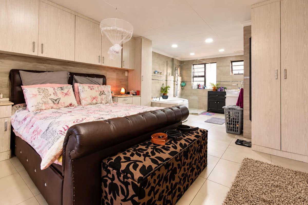 Spacious bedroom featuring extensive built-in cabinetry and an integrated open-plan en-suite bathroom with a shower and bathtub.