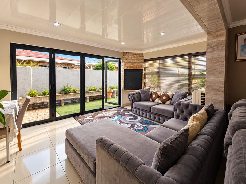Spacious living room featuring modern tiled flooring, a corner fireplace with stone cladding, and large bi-fold doors opening to a private patio area.