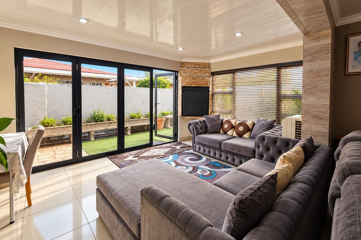 Spacious living room featuring modern tiled flooring, a corner fireplace with stone cladding, and large bi-fold doors opening to a private patio area.