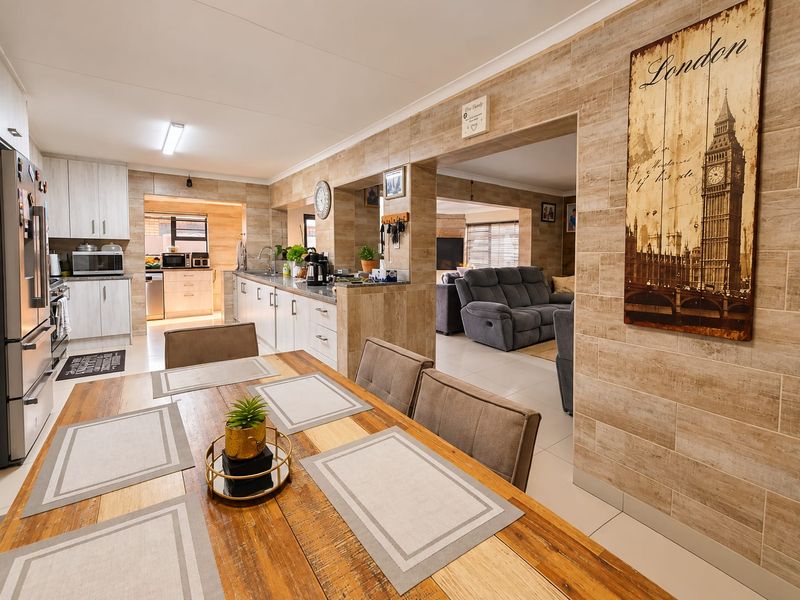 Spacious open-plan kitchen and dining area featuring modern cabinetry, stone-look wall tiles, and seamless flow into the adjacent living space.