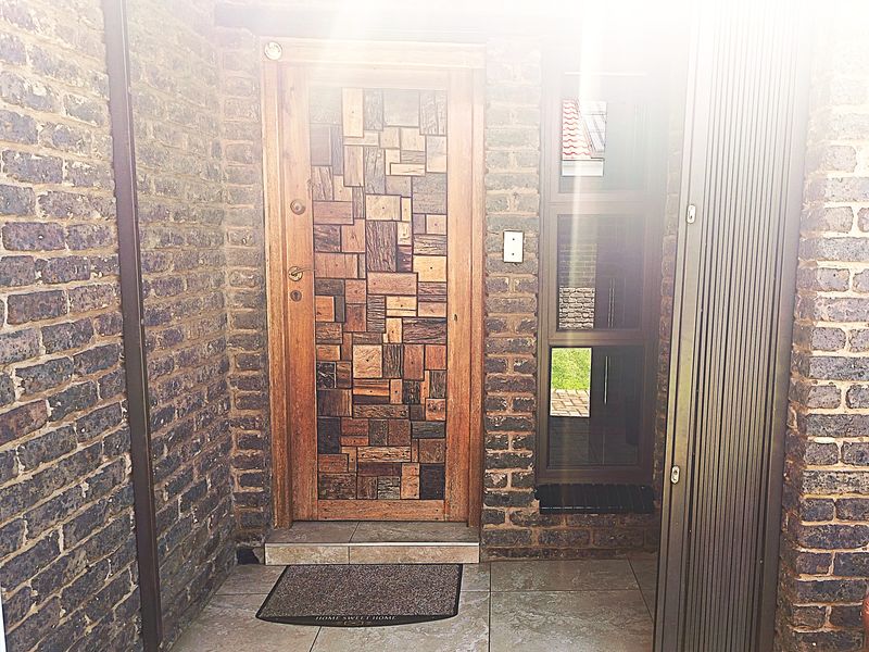 A welcoming entrance featuring a unique custom timber mosaic front door, set within durable face brick walls and complemented by tiled flooring.