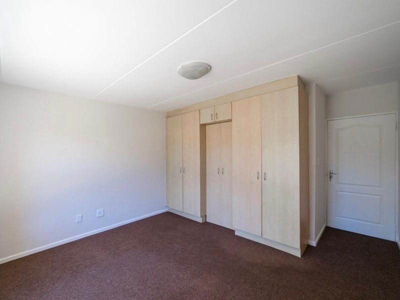 A clean, empty bedroom featuring neutral walls, brown carpeting, and ample built-in cupboard storage space.