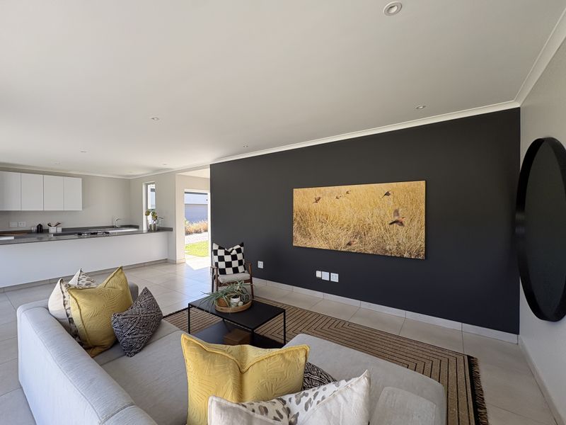 Modern open-plan living area featuring a sleek kitchen with built-in cabinetry and a spacious lounge area with a striking dark feature wall.