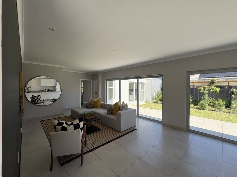 Spacious living area featuring large sliding glass doors that provide seamless access to the garden and patio, complemented by neutral tiled flooring.