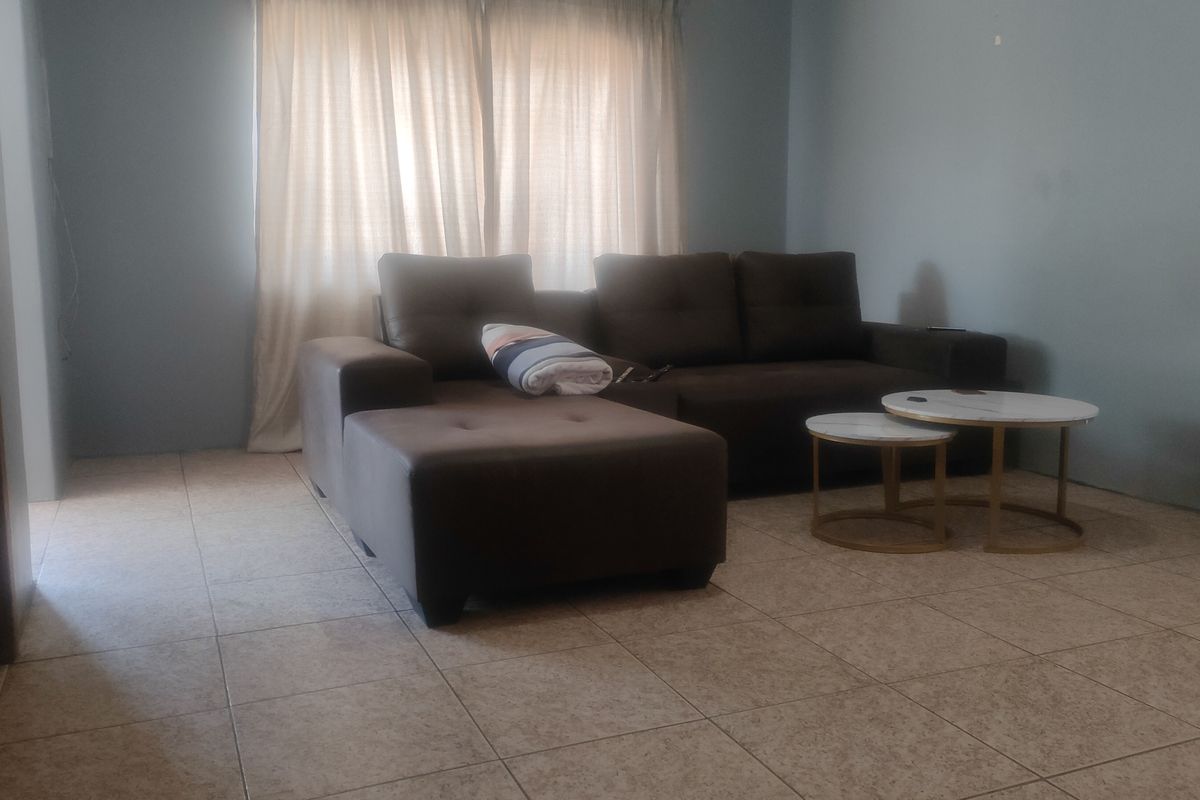 A living room area featuring neutral tiled flooring and window treatments, providing a functional space ready for personalization.