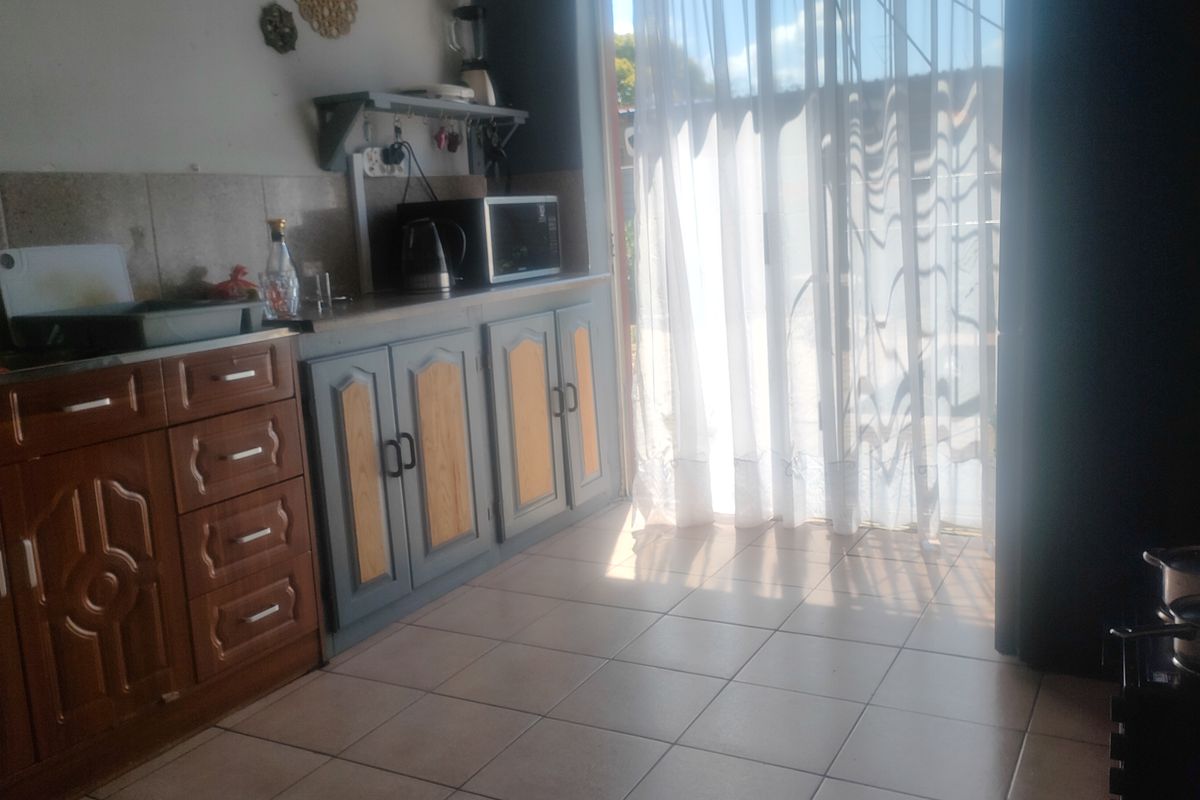 A kitchen area featuring tiled flooring, built-in cabinetry with a mix of finishes, and a sliding glass door providing natural light.
