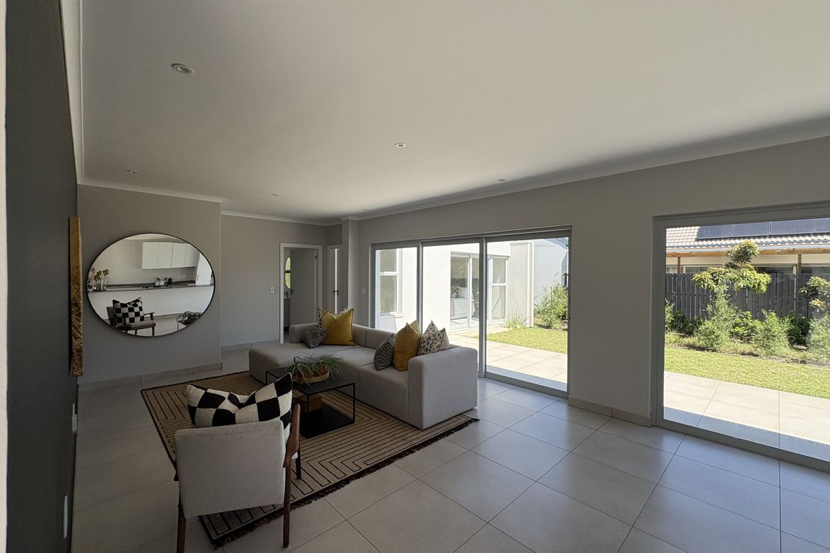 Spacious living area featuring large sliding glass doors that provide seamless access to the garden and patio, complemented by neutral tiled flooring.