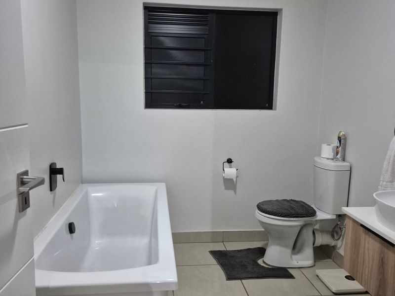 A modern, well-maintained bathroom featuring a freestanding bathtub, a vanity with basin, and a toilet, finished with neutral floor tiles and clean wall finishes.