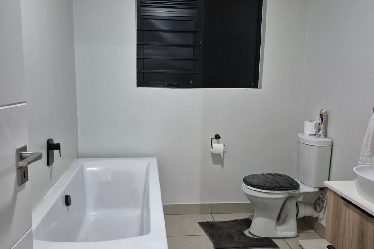 A modern, well-maintained bathroom featuring a freestanding bathtub, a vanity with basin, and a toilet, finished with neutral floor tiles and clean wall finishes.
