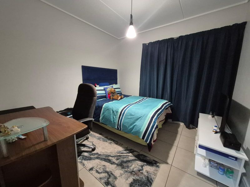 A functional bedroom featuring tiled flooring and neutral wall finishes, providing a comfortable and practical living space.