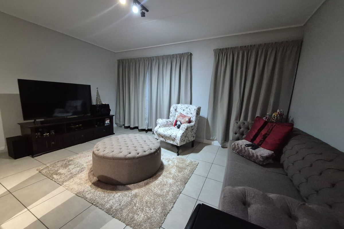 A comfortable living room featuring neutral tiled flooring and modern track lighting, providing a functional and well-lit space for relaxation.